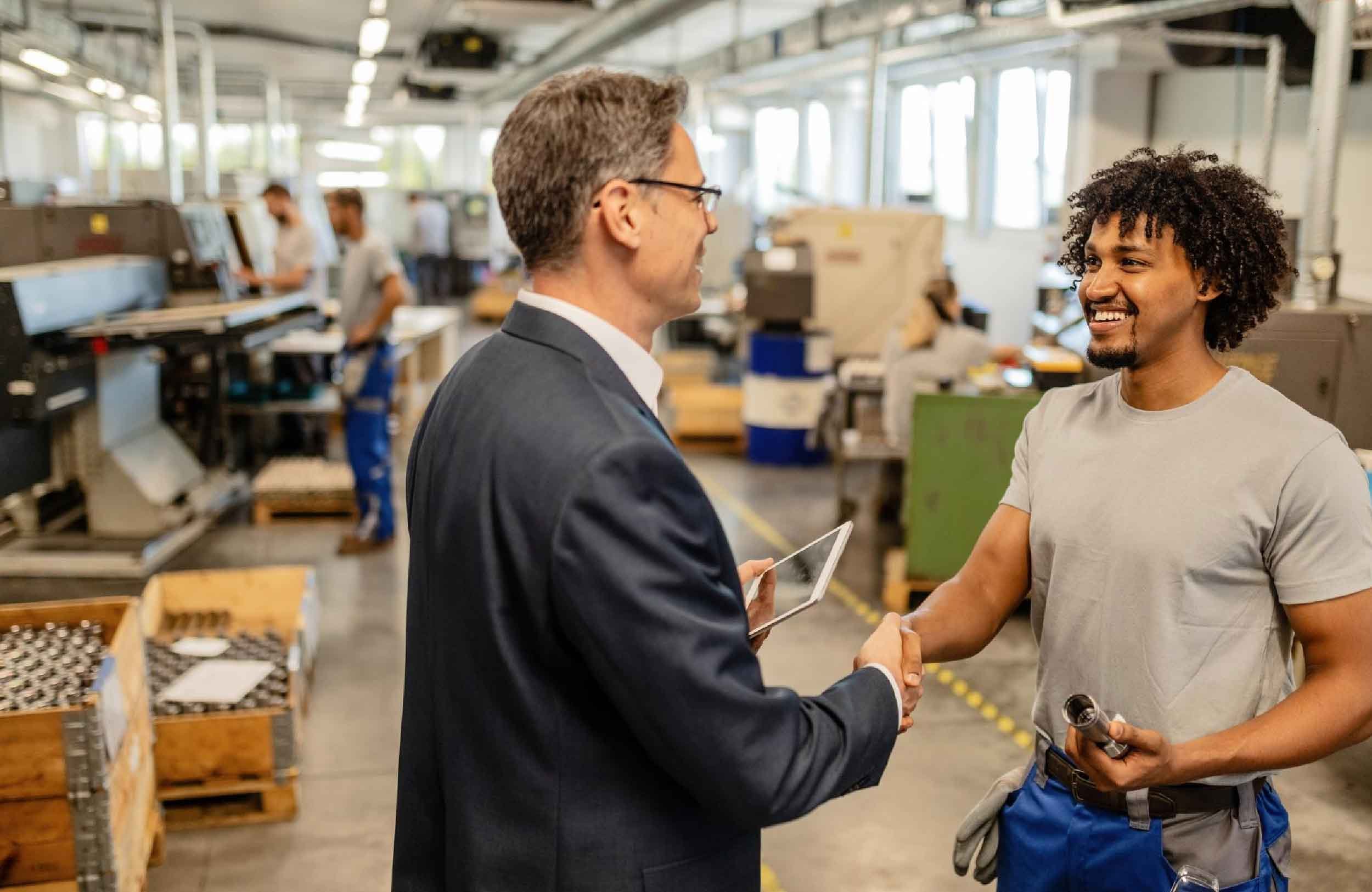 75% maintenance rule happy black manual worker shaking hands with company engineer factory