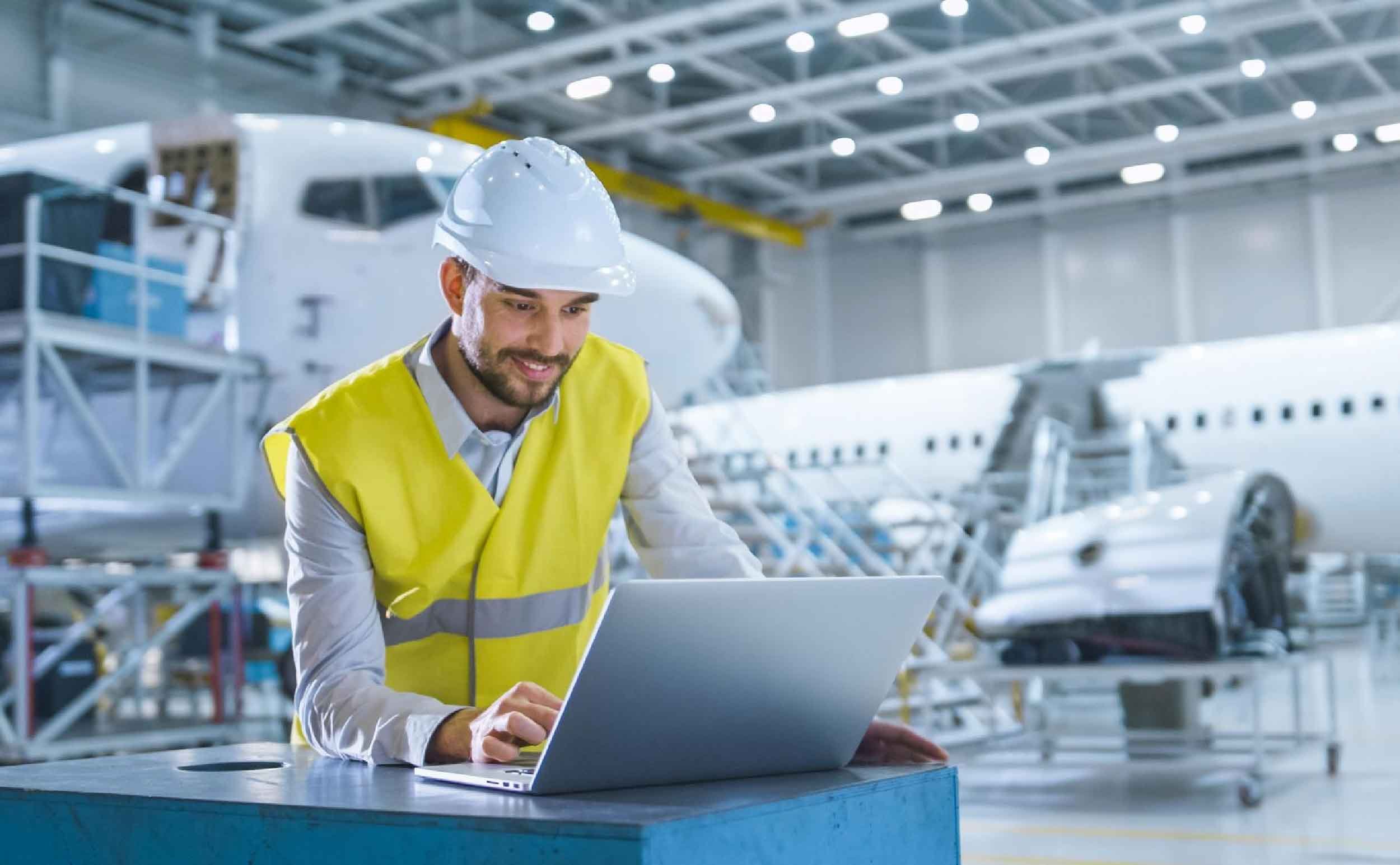 cloud based cmms man construction suit works hangar with laptop