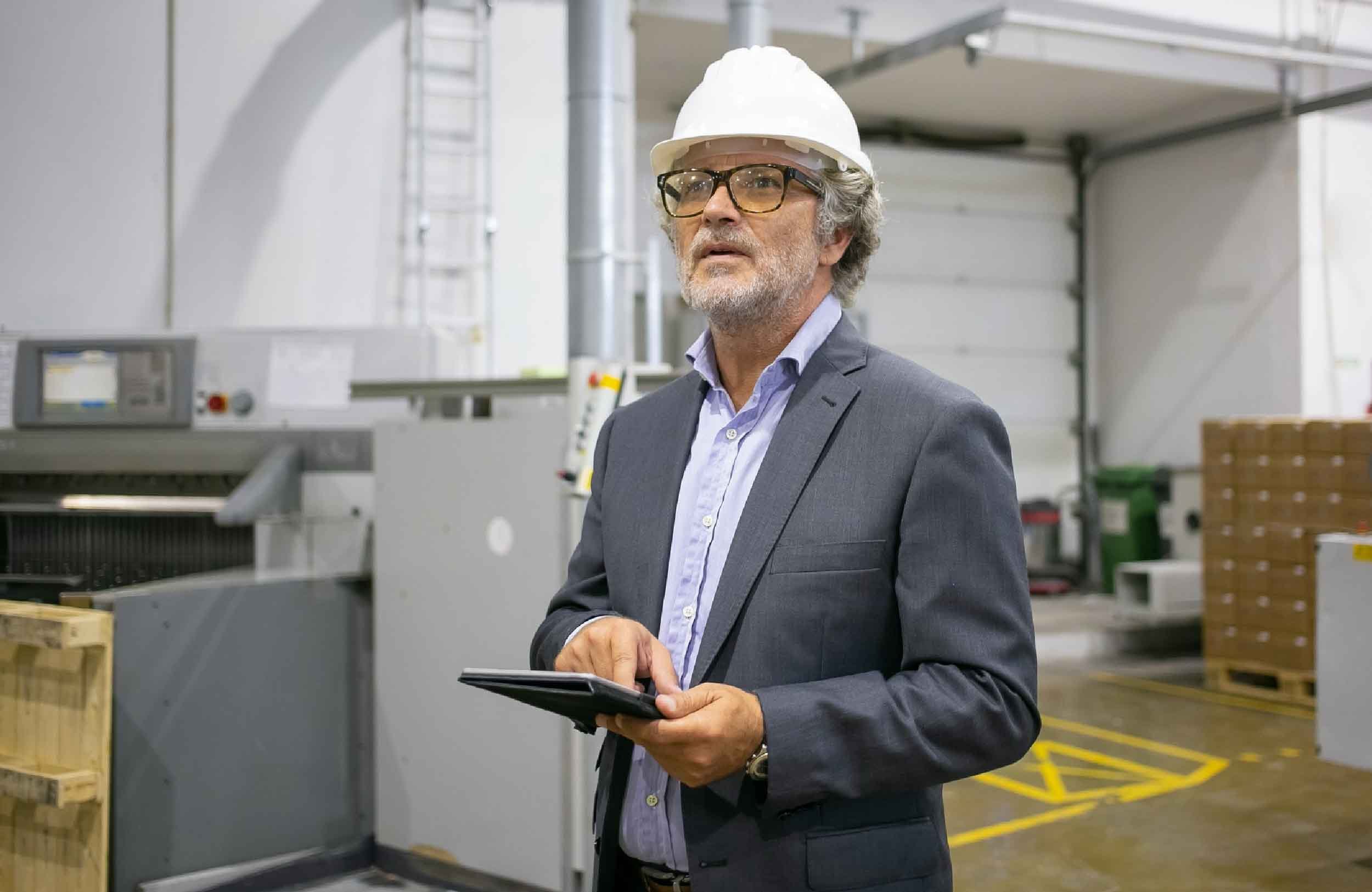 cmms implementation services pensive man protective helmet holding tablet looking away