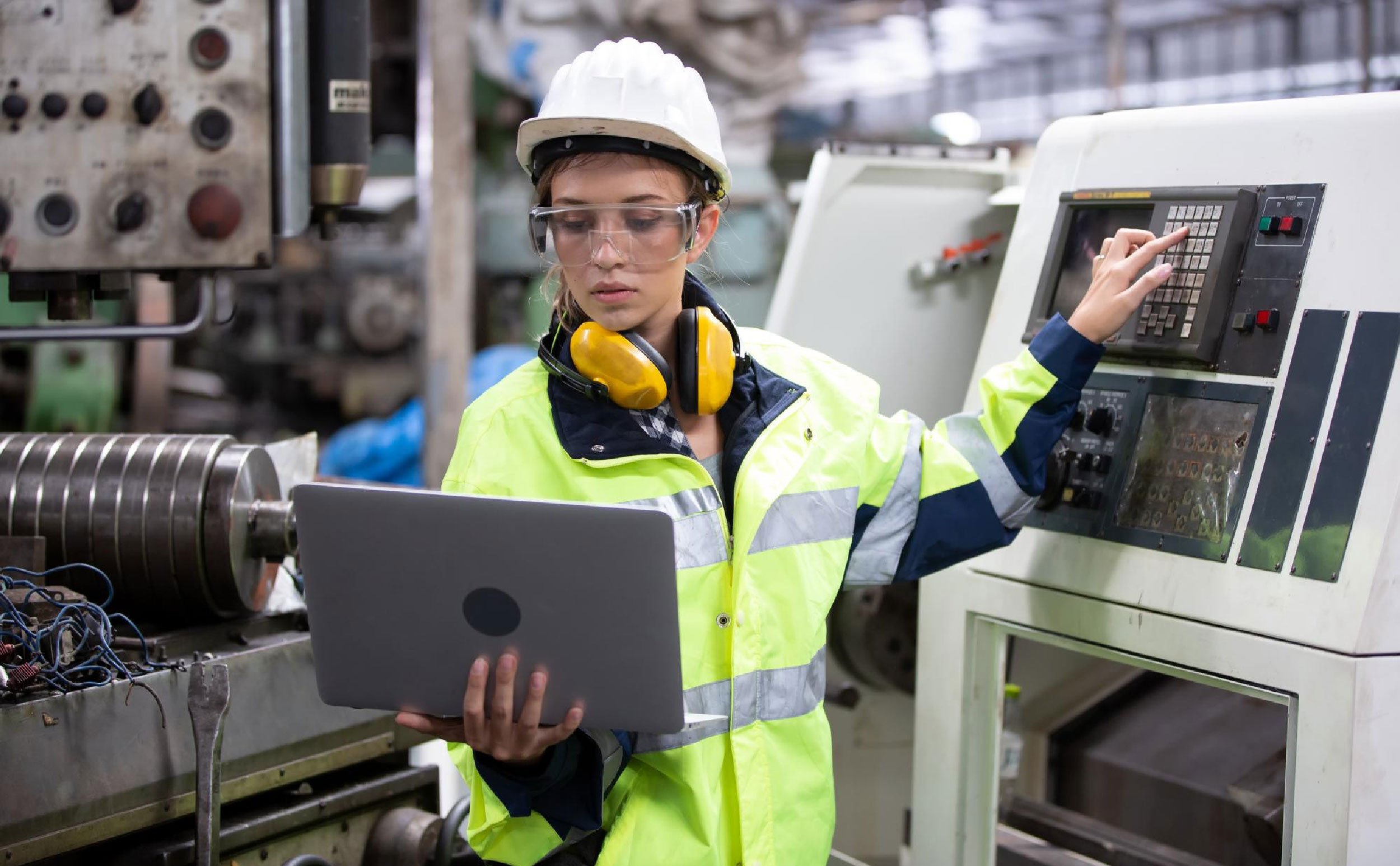 cmms scales maintenance engineer using laptop while operating machine factory