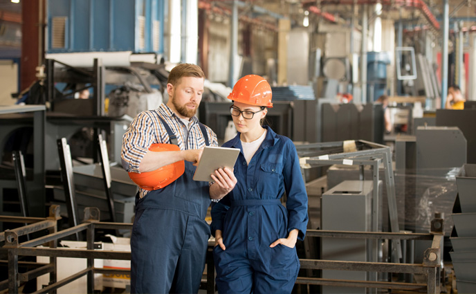 cmms software implemenation pitfalls technician overalls showing his colleague online data tablet explaining