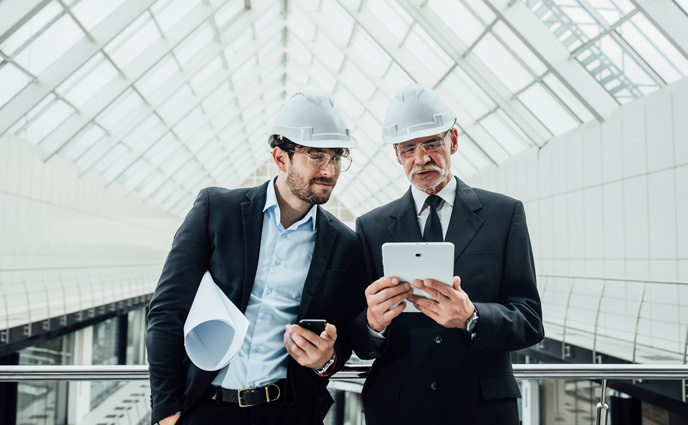 cmms vs cafm two entrepreneurs standing holding tablet new buildings near glass roof