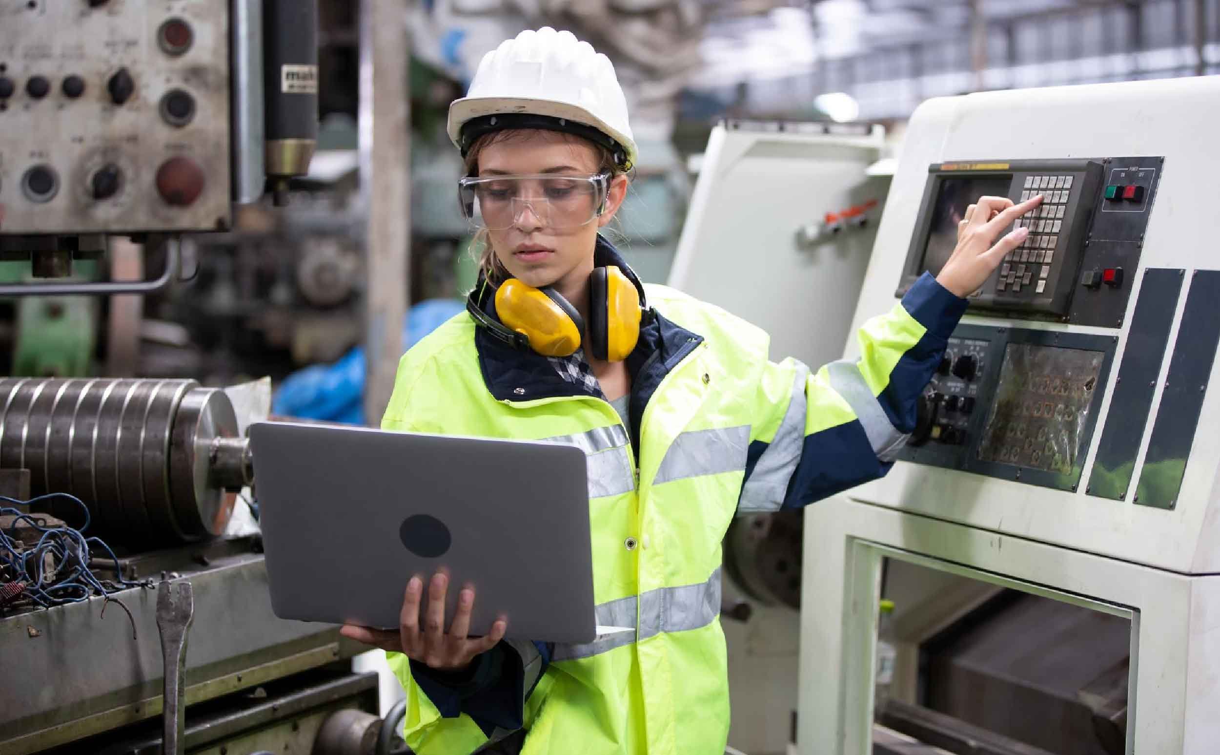 equipment reliability engineer using laptop while operating machine factory