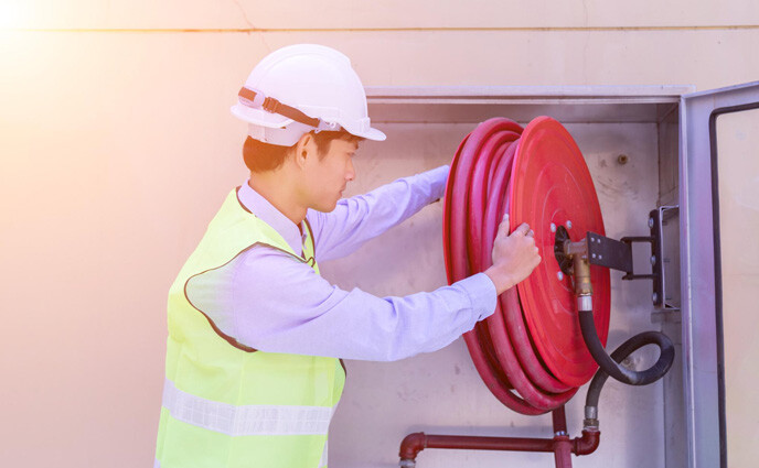 hotel maintenance pain points man working with red fore hose against wall