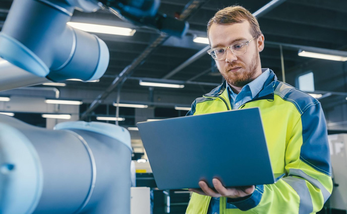 maintenance management biases man green safety vest is looking laptop while standing warehouse