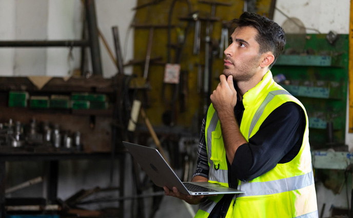 maintenance management biases man working in factory thinking holding laptop