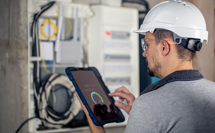 new cmms software man electrical technician checking switchboard using tablet