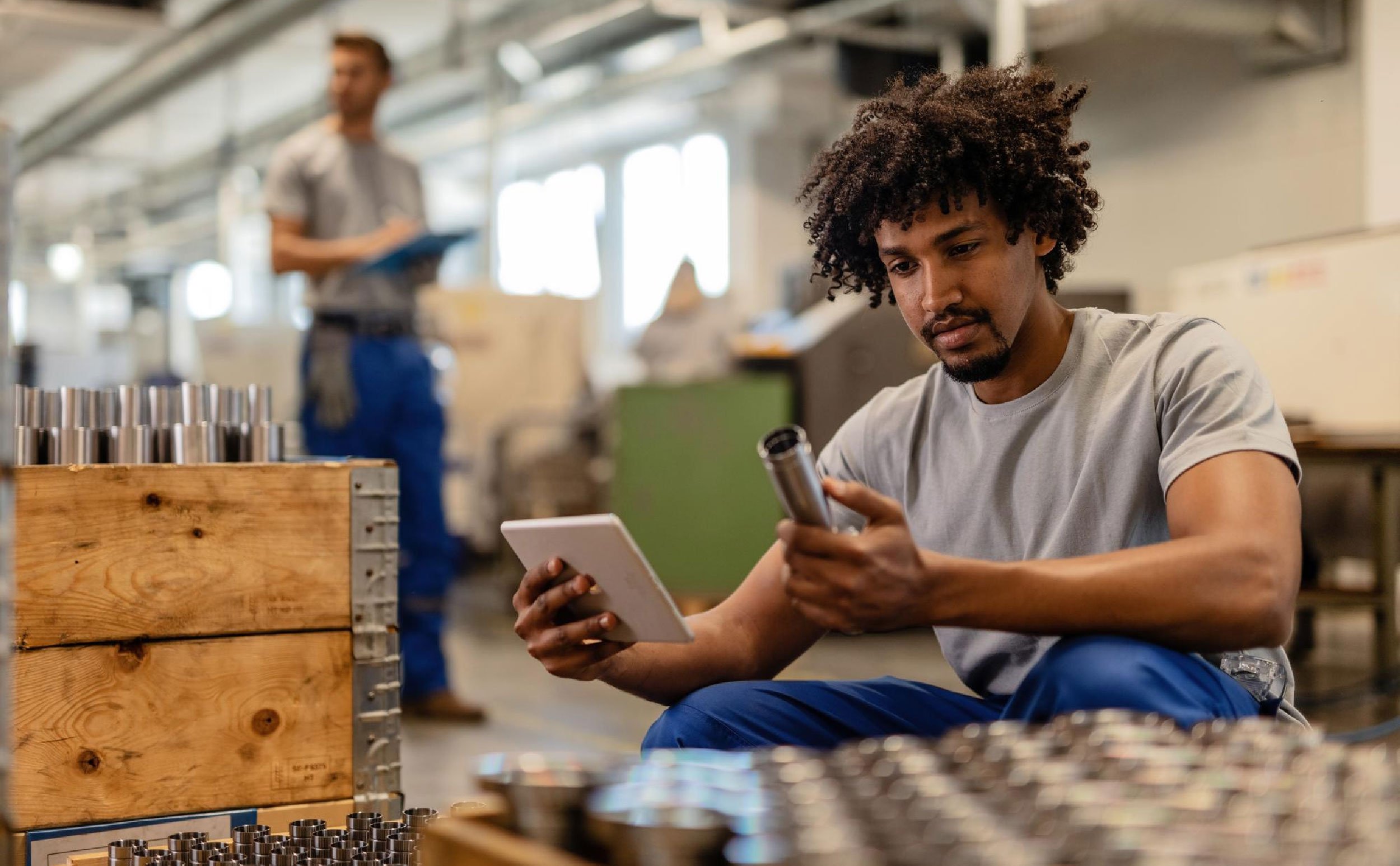 work order chat african american manual worker using touchpad while examining manufactured stainless steel rods factory
