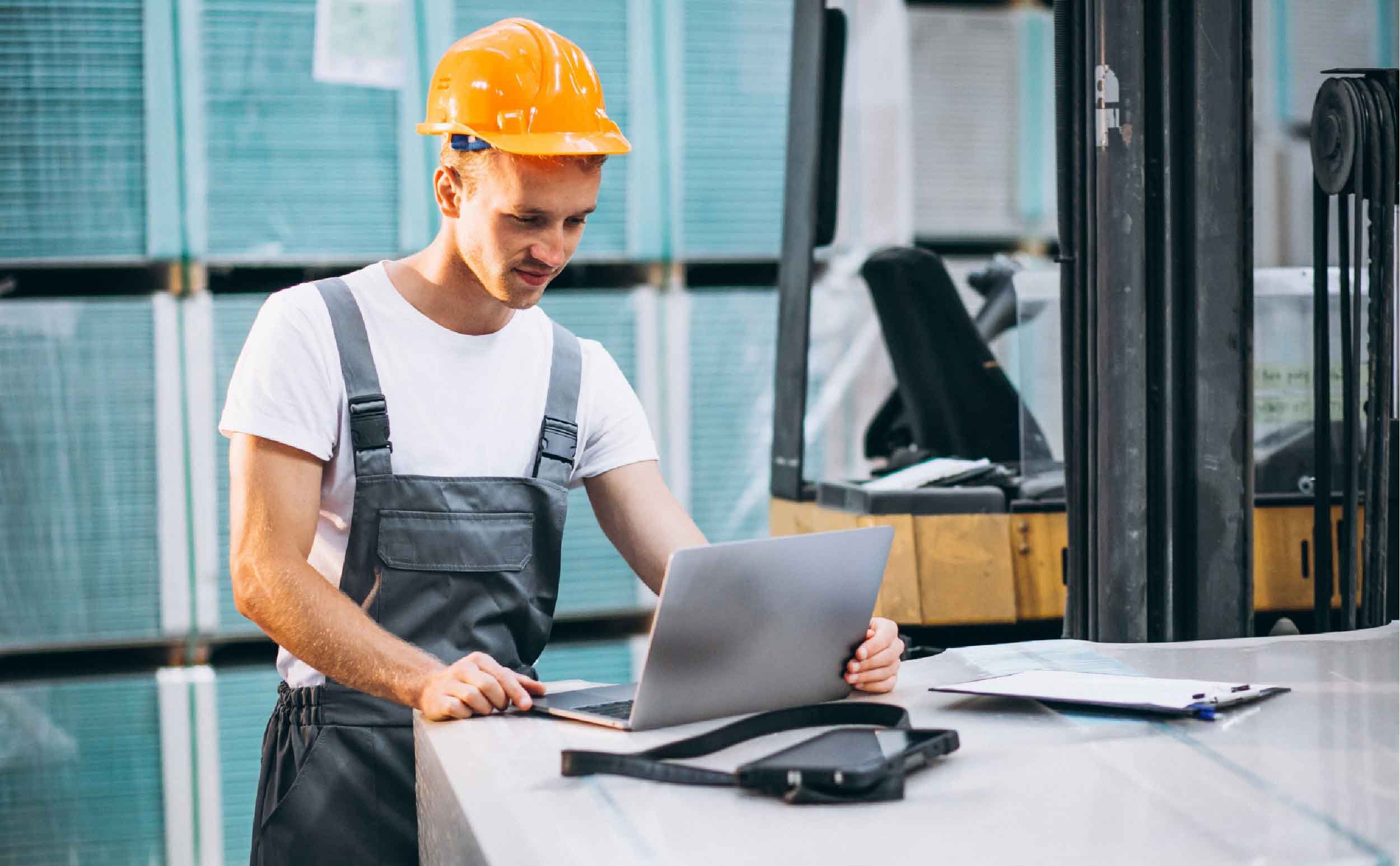 work order prioritization young man working warehouse with laptop