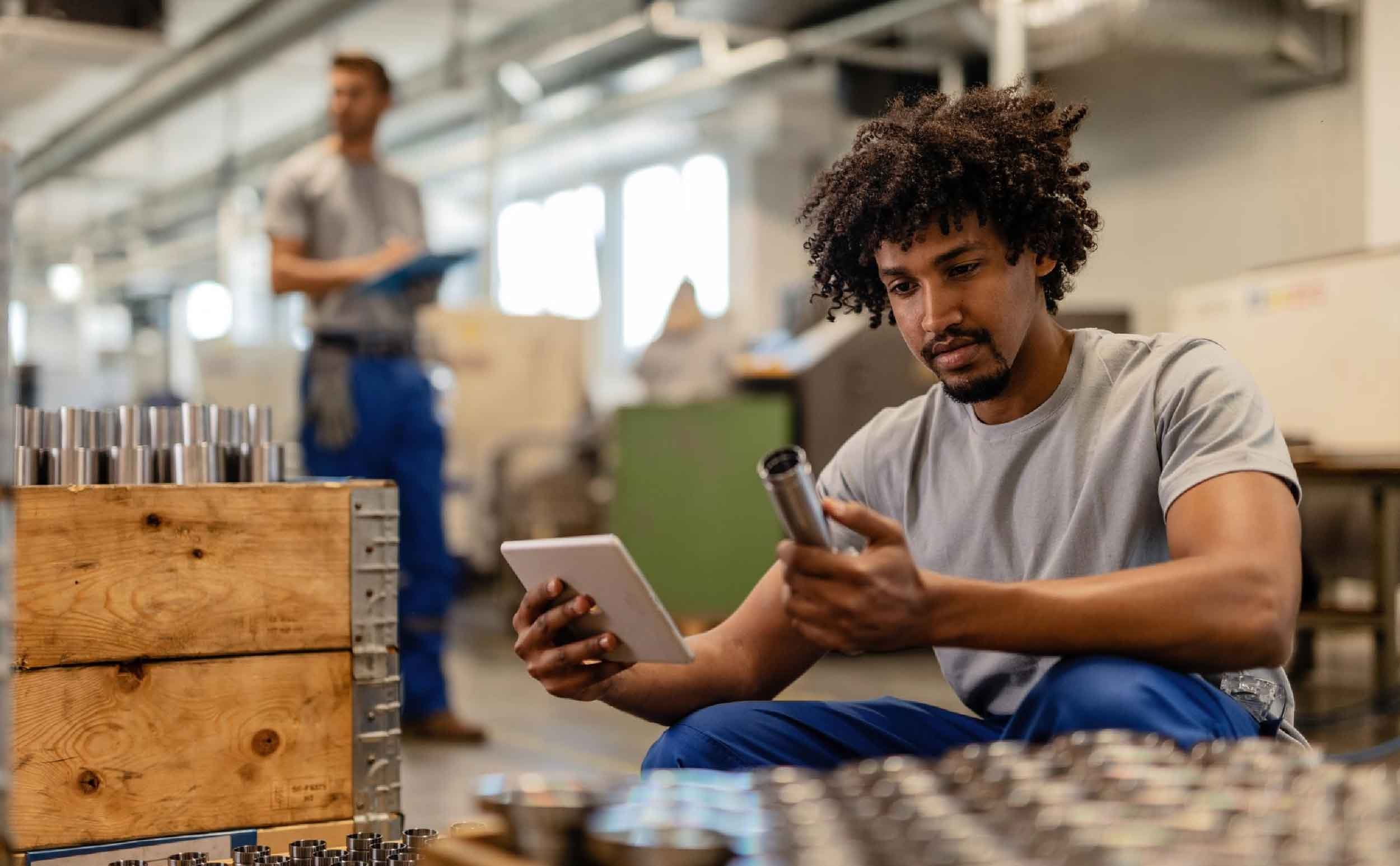 work order process african american manual worker using touchpad while examining manufactured stainless steel rods